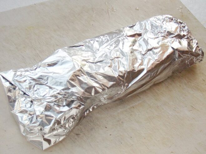 Step 5: Resting the glazed pork medallions in foil to finish cooking Pork medallions coated in sauce being wrapped tightly in aluminum foil to rest.