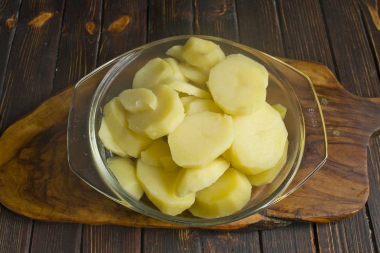 Parboiling Potato Slices for the Casserole Base Sliced potatoes being boiled in a pot of water.