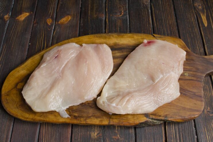 Prepping the Chicken Fillet for a Juicy Result A raw chicken fillet on a cutting board, being patted dry with a paper towel.