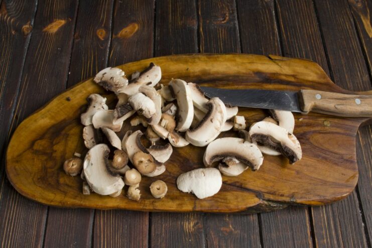 Sautéing Mushrooms to Enhance Their Earthy Flavor Sliced button mushrooms being sautéed in a skillet.