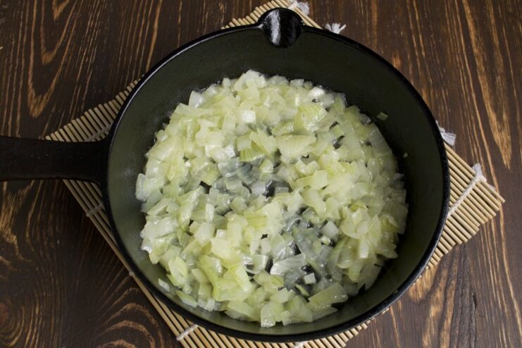 Sautéing onions in a pan until soft and translucent, the first step to a flavorful ragout. Chopped onions being sautéed in a hot pan with oil.