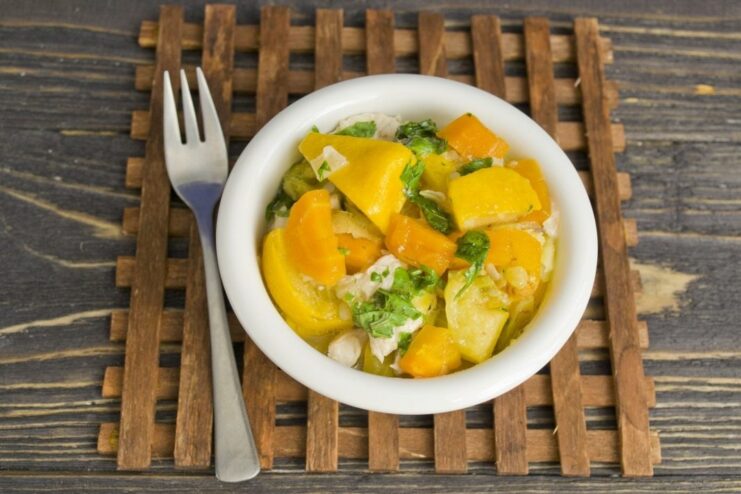 Serving the hot and comforting vegetable stew A serving of the finished vegetable stew with chicken and pattypan squash in a white bowl.