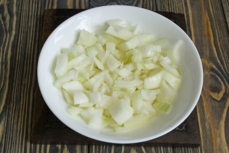 Finely chopping an onion to add flavor to the ragout A pile of finely chopped yellow onion on a cutting board.