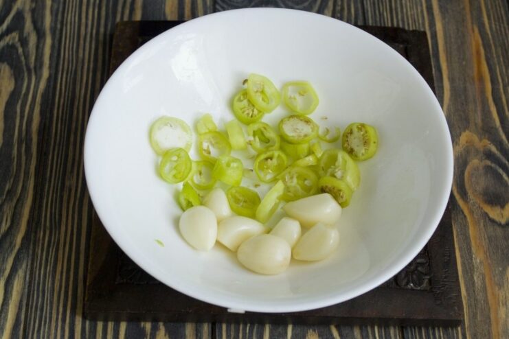Preparing the aromatics: garlic and chili Peeled garlic cloves and sliced green chili pepper ready for the ragout.
