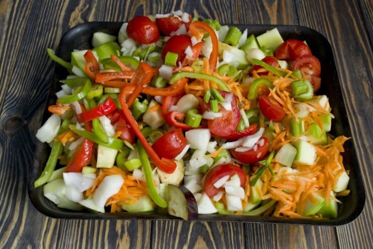 Vegetables seasoned and ready for roasting on a sheet pan A mix of chopped vegetables seasoned with spices on a baking sheet before roasting.