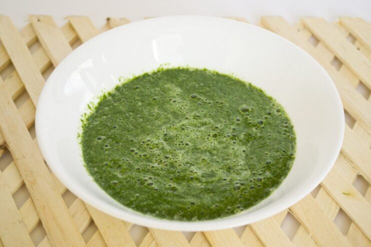 Step 3: Creating the spinach puree for the pasta dough. A blender jar containing a smooth green puree of blanched spinach and an egg.