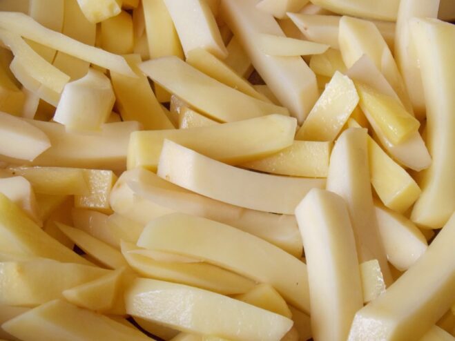 Sliced potatoes being pan-fried in a skillet until they start to turn golden.