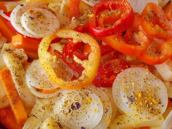 Bell peppers, onions, and spices are added to the skillet with potatoes and pumpkin.