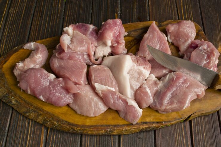 Searing pork pieces in a pan to lock in the juices for the plov. Pieces of pork being seared in a hot pan until golden brown.