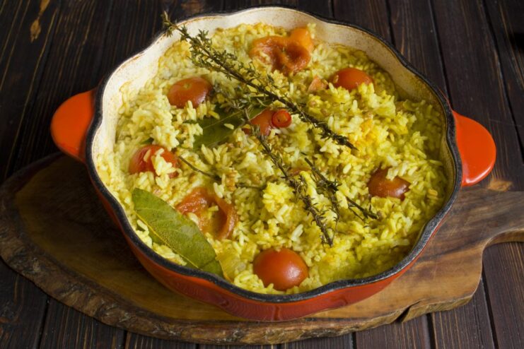 Covering the pot to simmer the plov until the rice is perfectly cooked. A dutch oven with a lid on, simmering on a stove to cook the plov.