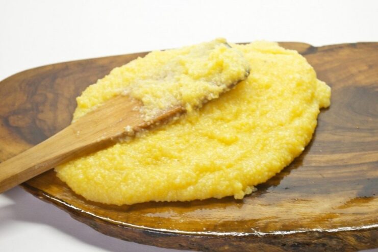 Preparing Polenta: Spreading the Cooked Mixture to Cool Hot, cooked polenta being spread evenly on an oiled surface to cool and set.