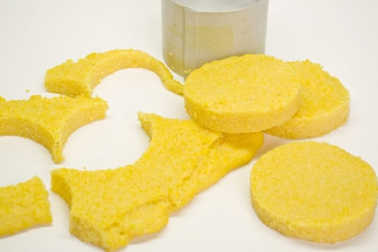 Shaping the Polenta Cakes with a Culinary Ring Using a round culinary ring to cut out cakes from a slab of cooled polenta.