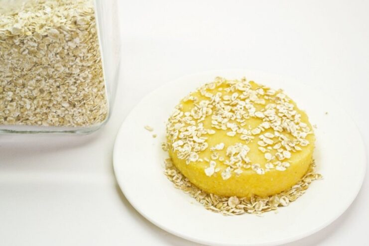 Coating Polenta Cakes in Oats for a Crispy Texture Round polenta cakes being coated in a layer of rolled oats before frying.