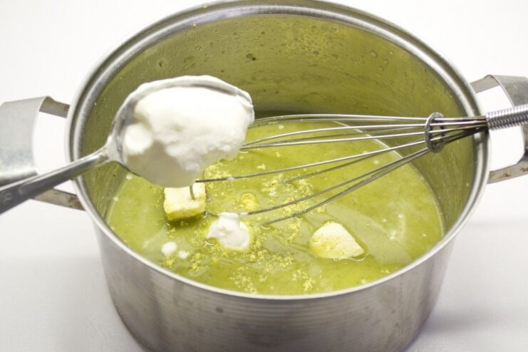 Finishing the Creamy Brussels Sprout Sauce on the Stove A green sauce being whisked in a saucepan on the stove to thicken.
