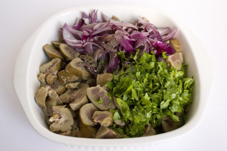 Building the Savory Filling for the Pudding A pan with sautéed red onions and chopped kidneys, with fresh parsley being added.