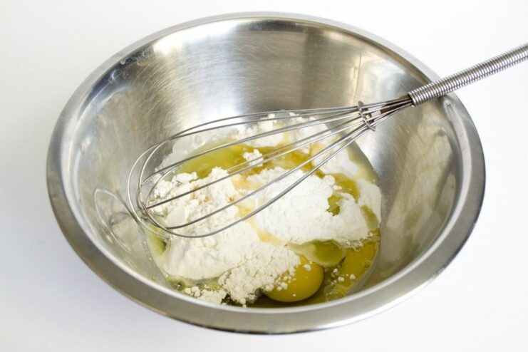 Whisking a Smooth and Light Batter for the Pudding A bowl with liquid batter being whisked, containing eggs, milk, and flour.