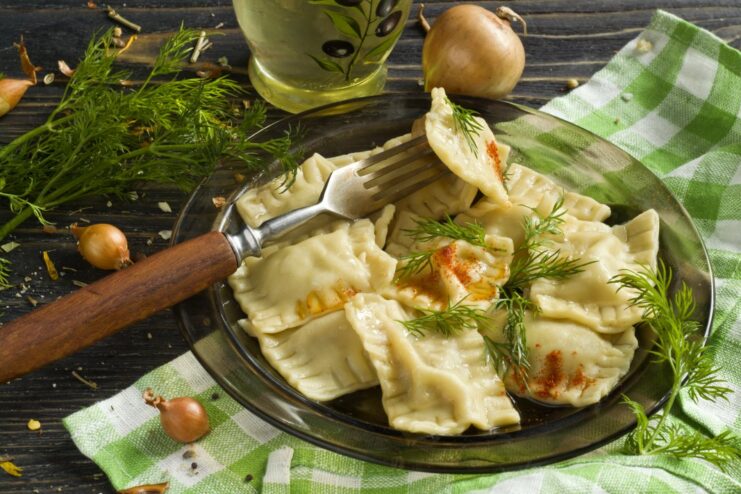 A plate of freshly cooked ravioli with meat filling, garnished with herbs.
