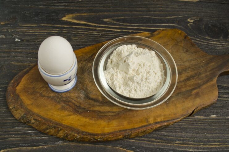 Simple Ingredients for Perfect Ravioli Dough: Flour, Salt, and Egg Ingredients for pasta dough on a surface: a pile of flour, salt, and a whole egg.
