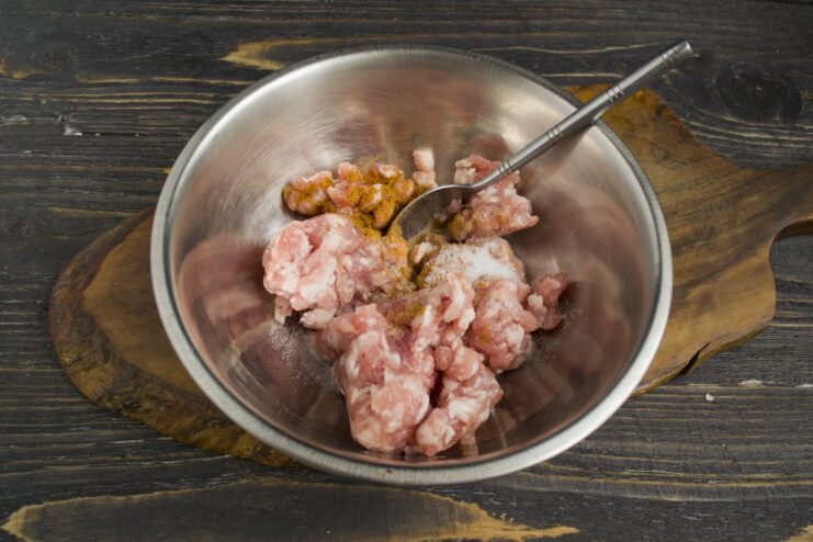 Creating a Flavorful Meat Filling for Ravioli A bowl of ground pork with curry powder being mixed for the ravioli filling.