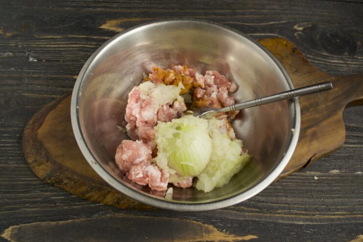 Adding Grated Onion for a Juicier Ravioli Filling Finely grated onion being added to a bowl of seasoned ground pork.