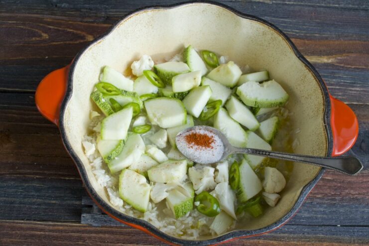 Step 5: Adding water and seasonings before simmering. Water being poured into the pan with rice and vegetables to cook.