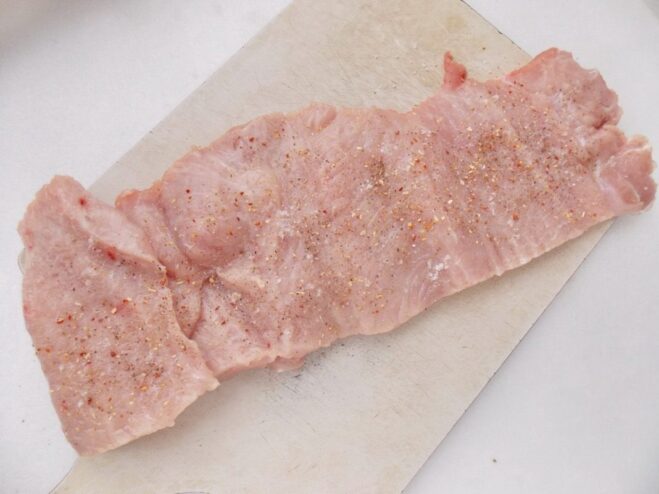 How to Butterfly and Season Pork Loin for a Roll A piece of pork loin cut open butterfly-style and seasoned with salt and pepper.