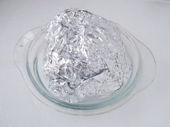 Preparing the Pork Roll for Roasting in the Oven A pork roll wrapped in aluminum foil, placed in an oven-safe dish, ready for baking.