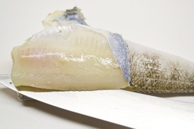 Preparing the Fish: Cleaning and Scaling A whole fish on a cutting board being cleaned and prepared for filleting.