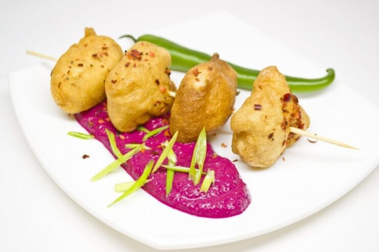 The Finished Dish: A Perfect Harmony of Flavors and Colors The final plated dish of crispy battered fish served alongside a vibrant beetroot purée.
