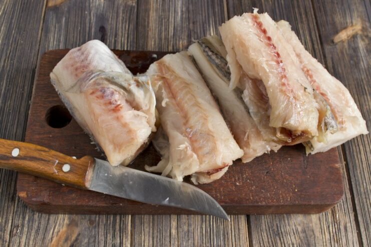 How to Properly Fillet a Pollock for Fish Cakes Hands filleting a pollock fish on a cutting board.