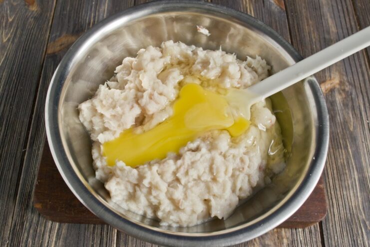 Adding Eggs to Bind the Fish Cake Mixture Cracked eggs being added to the minced fish mixture in a bowl.
