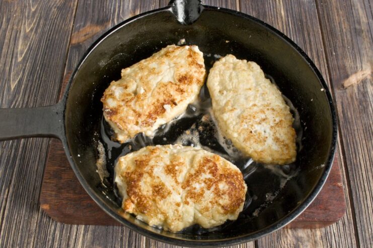 Frying Fish Cakes to a Perfect Golden Brown Pollock fish cakes sizzling in a hot frying pan with oil.