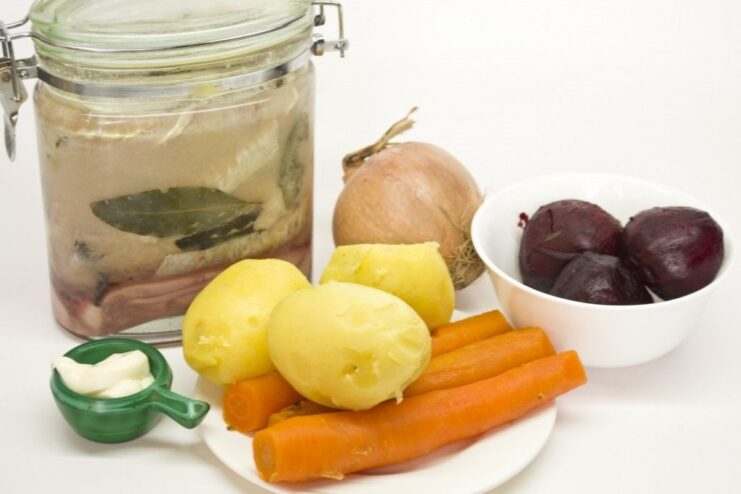 All the fresh ingredients needed for the Shuba Salad Roll: cooked beets, carrots, potatoes, onion, and home-cured herring. Ingredients for Shuba Salad Roll laid out: cooked vegetables, onion, and herring fillets.