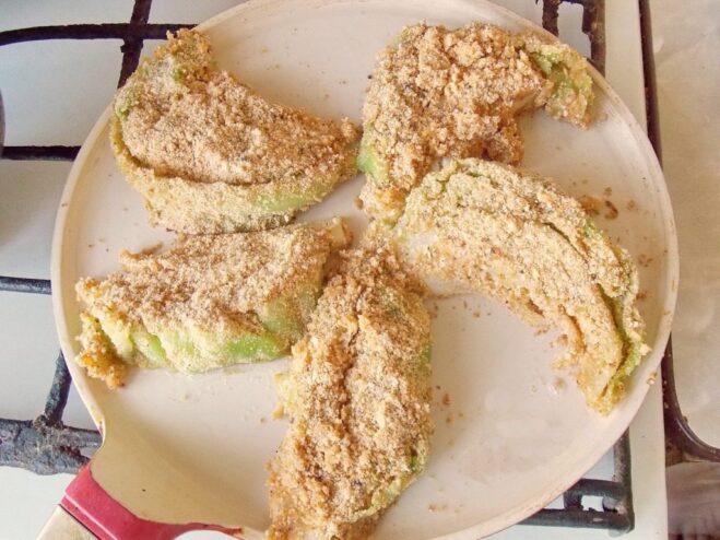 Placing breaded cabbage schnitzels onto a hot frying pan Breaded cabbage wedges being placed into a hot pan with oil to fry.