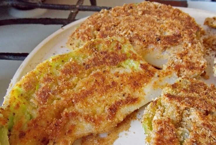 Frying cabbage schnitzels until they are crispy and golden Cabbage schnitzels frying in a pan, turning a beautiful golden-brown color.