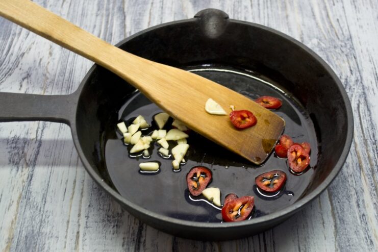 Infusing Oil with Garlic and Chili for an Aromatic Base Chopped garlic and chili pepper being sautéed in a pan with oil.