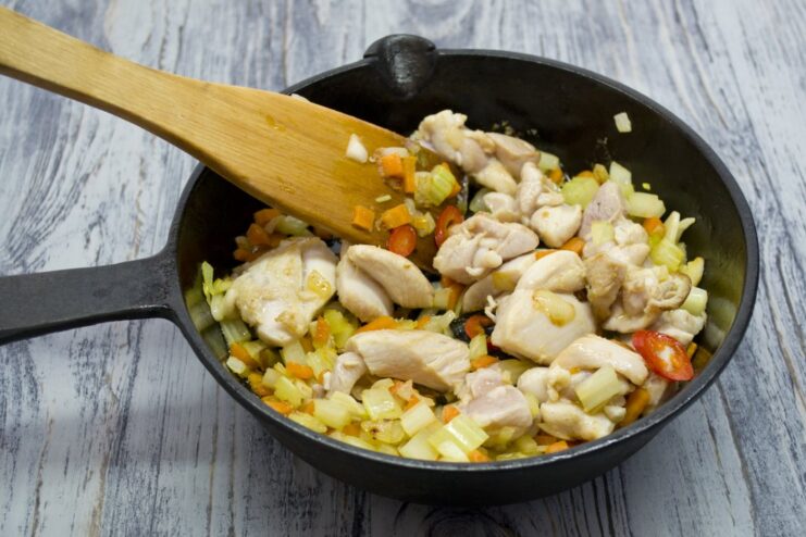 Combining the Seared Chicken with the Sautéed Vegetables Seared chicken pieces being added back to the pan with sautéed vegetables.