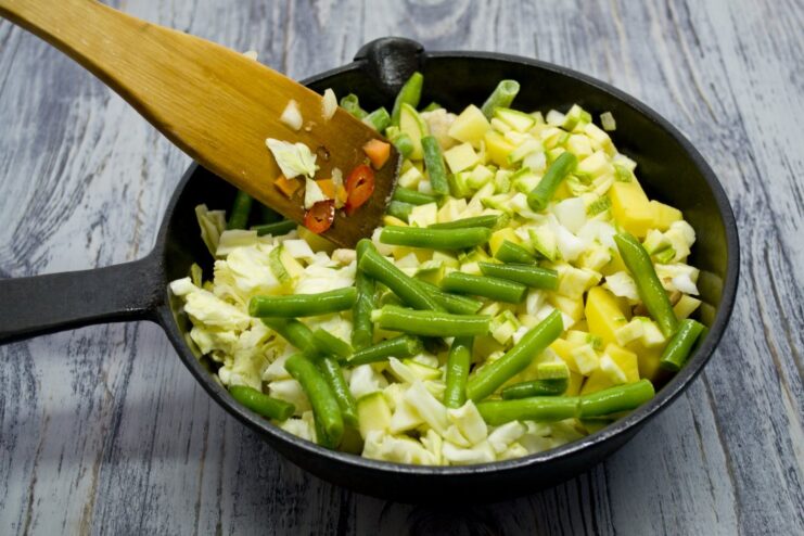 Adding Freshness with Green Beans and Zucchini Green beans and diced zucchini being added to the stew.