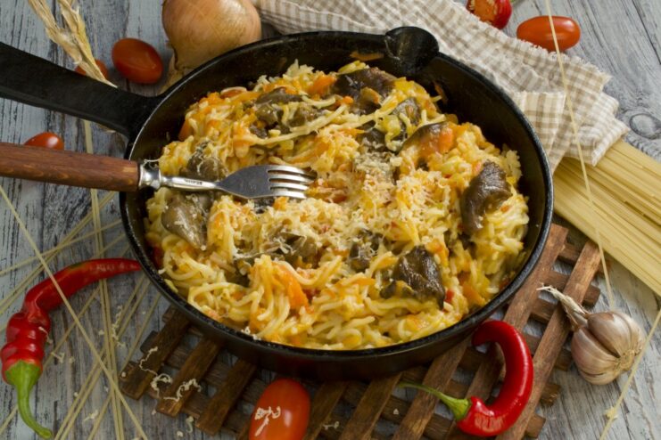A plate of ready-to-eat spaghetti with mushrooms, garnished with grated cheese.