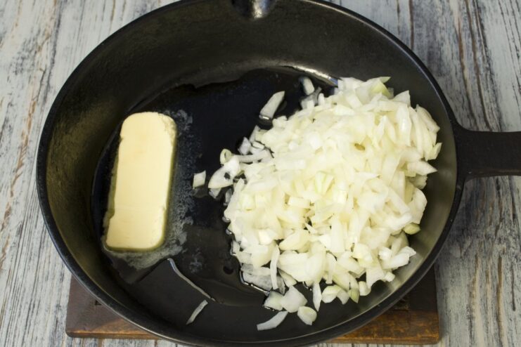 Sautéing chopped onion in a pan until translucent Chopped onion being sautéed in a hot pan with butter and oil.