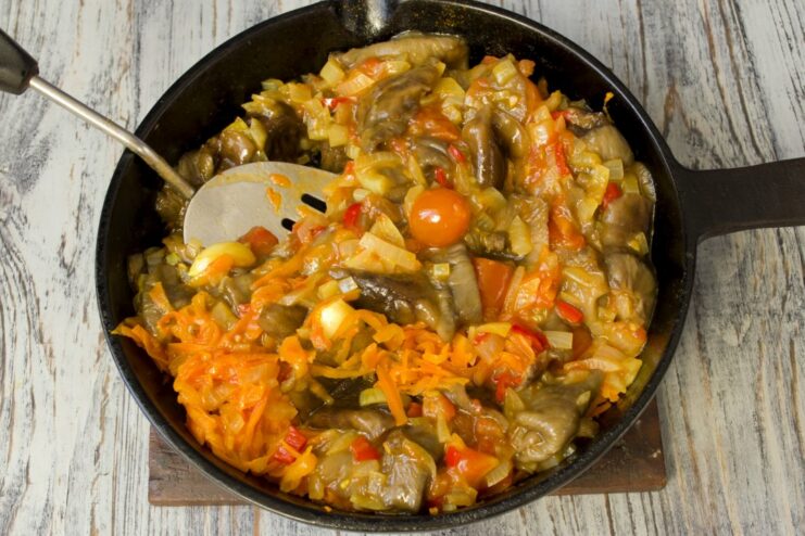 Combining mushrooms and carrots with the sauce base Boiled opyata mushrooms and grated carrots are added to the tomato and onion mixture in the pan.