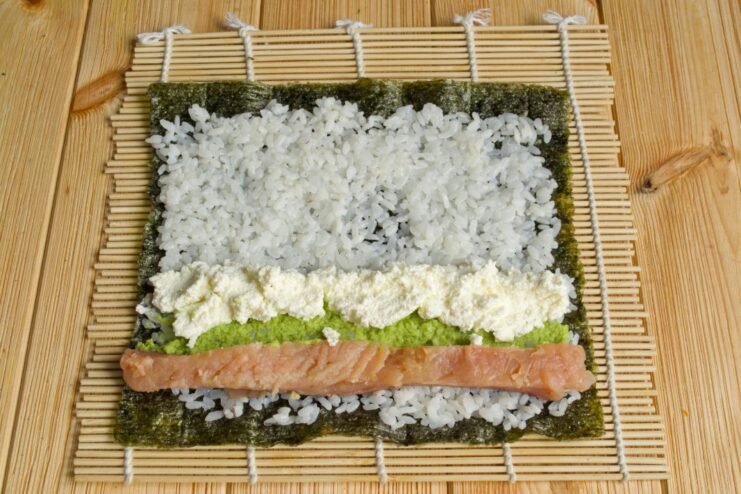 Creamy Filling: Adding a Line of Philadelphia Cream Cheese A strip of white cream cheese placed next to the salmon on the sushi rice.