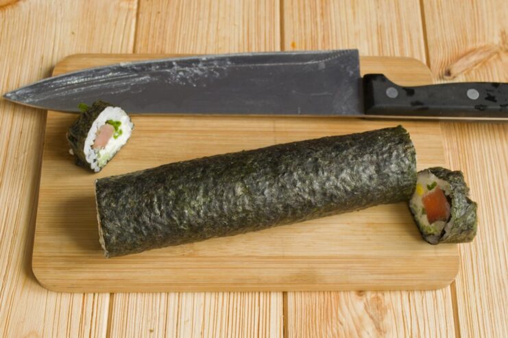 For a Perfect Look: Trimming the Uneven Ends of the Sushi Roll A sharp knife, wet with water, trimming the ends of the completed sushi roll.