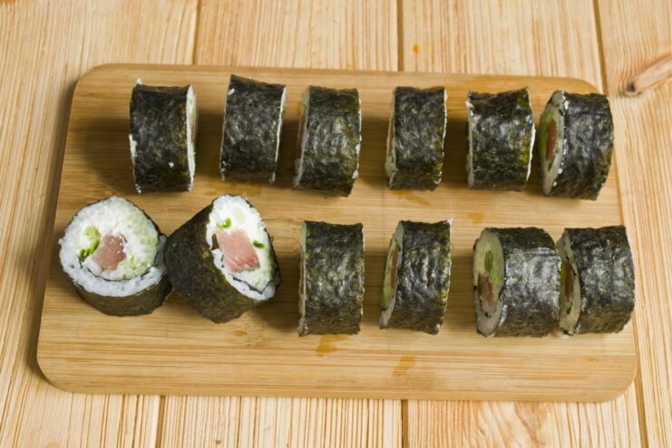How to Slice Sushi Rolls into Perfect, Even Pieces The long sushi roll being sliced into smaller, bite-sized maki pieces.