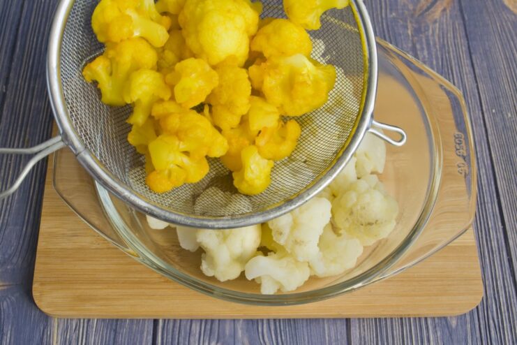 Adding Color: Blanching Cauliflower with Turmeric Cauliflower florets turning yellow as they are blanched in water with turmeric.