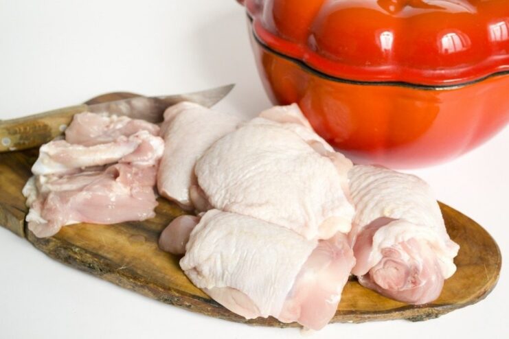 Searing chicken thighs to lock in the juices before braising. Raw, deboned chicken thighs being seared in a hot pan to a golden-brown crust.