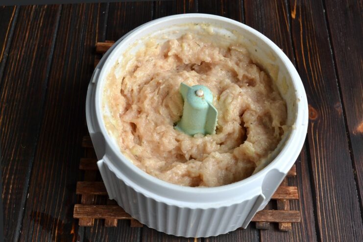 The chicken mixture being blended into a smooth, uniform paste inside a food processor.