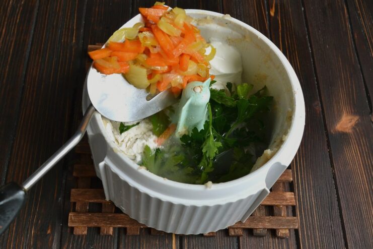A blender filled with sautéed vegetables, fresh herbs, and chicken broth, ready to be mixed into a gravy.