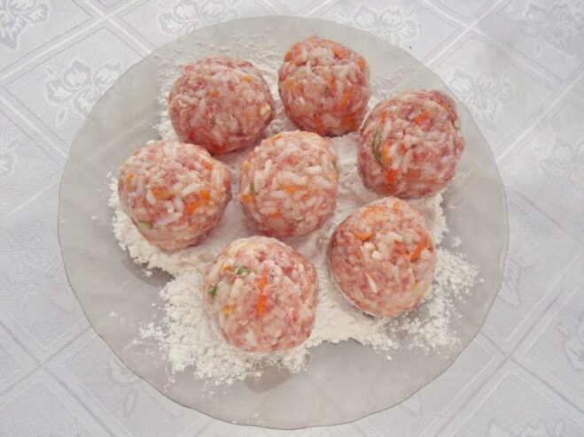 Hands rolling the ground meat mixture into a small, round meatball.