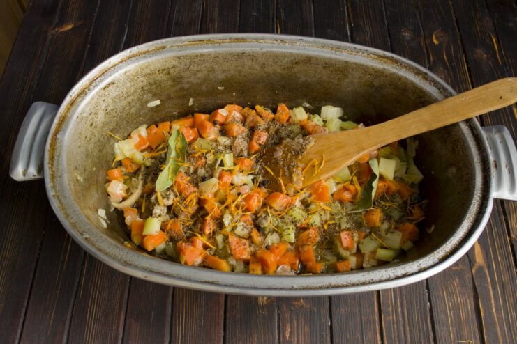 Toasting spices with vegetables to release their aroma for the plov A mix of whole spices like cumin and peppercorns being added to sautéed vegetables.